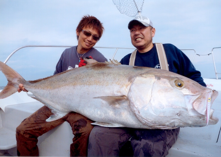 Two anglers holding a world-record amberjack caught fishing