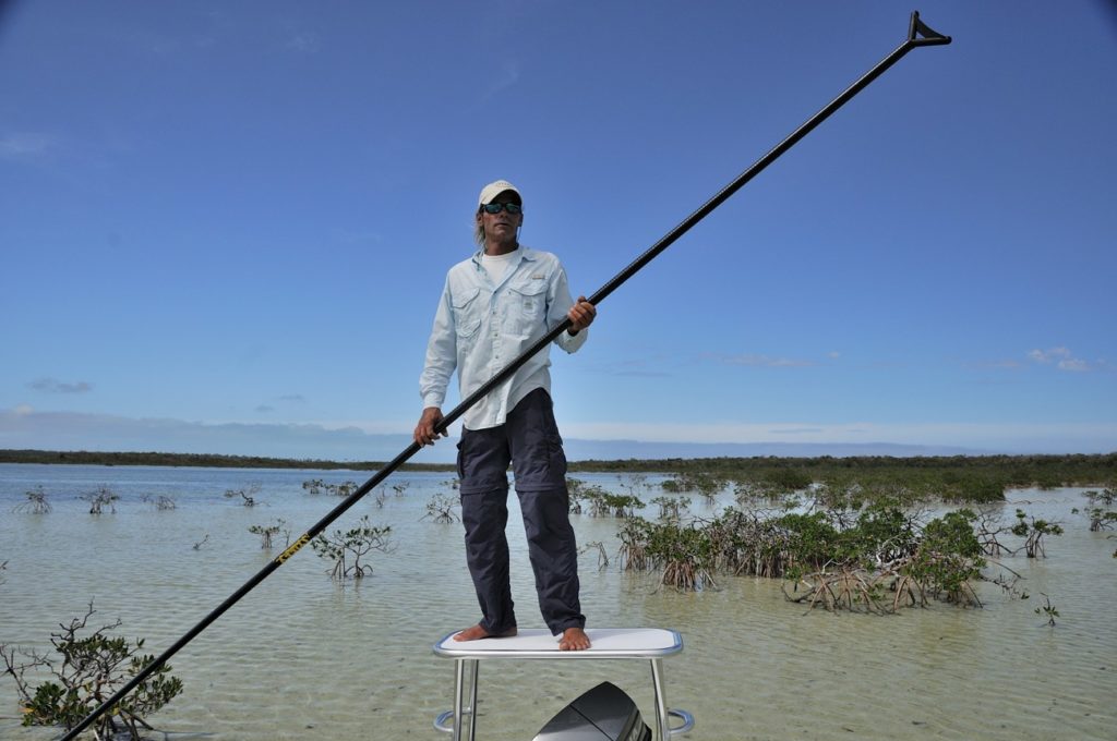 fly fisherman polling the flats of the Bahamas in a flats skiff fishing boat