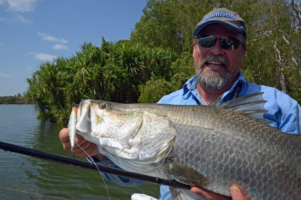 Australian angler holding a barramundi fish caught fishing a twitchbait fishing lure