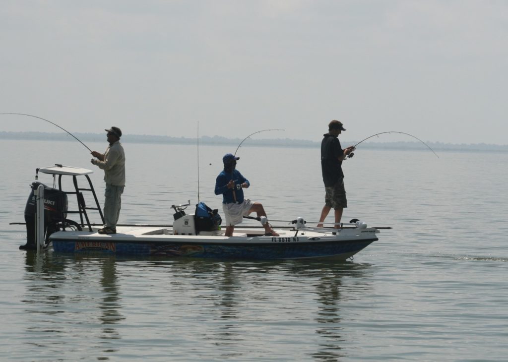 Anglers in a fishing skiff using saltwater spinning reels catching redfish