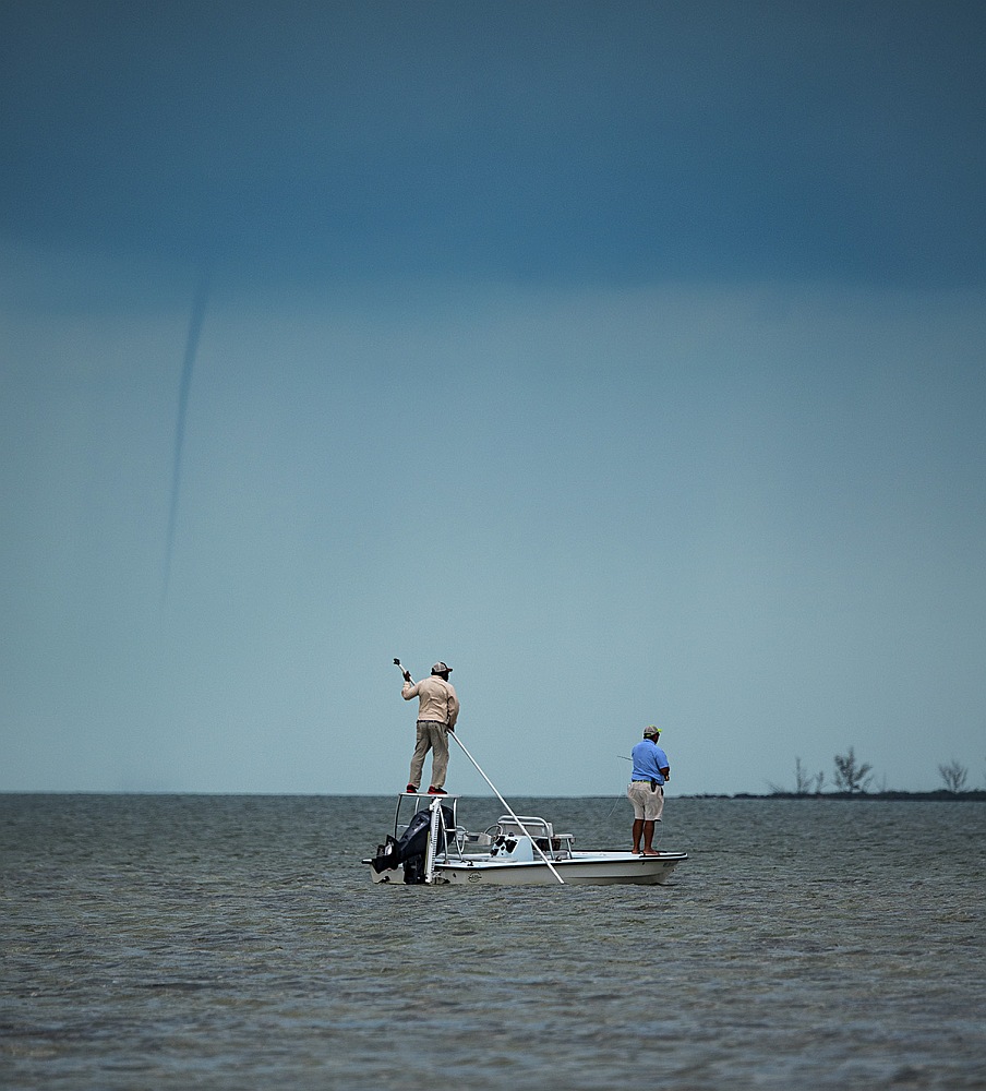 Anglers saltwater bonefish fishing under waterspout near North Riding Point Bonefish Club