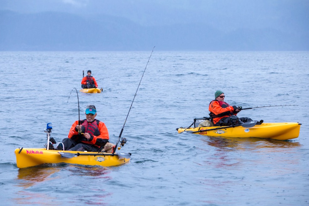 The bite is on for silver salmon as three kayak anglers fish in the rain.