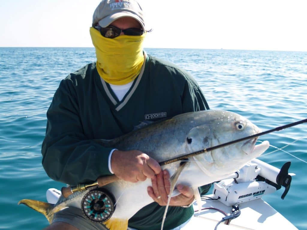Fisherman in buff holding a jack crevasse caught on a fly-fishing outfit