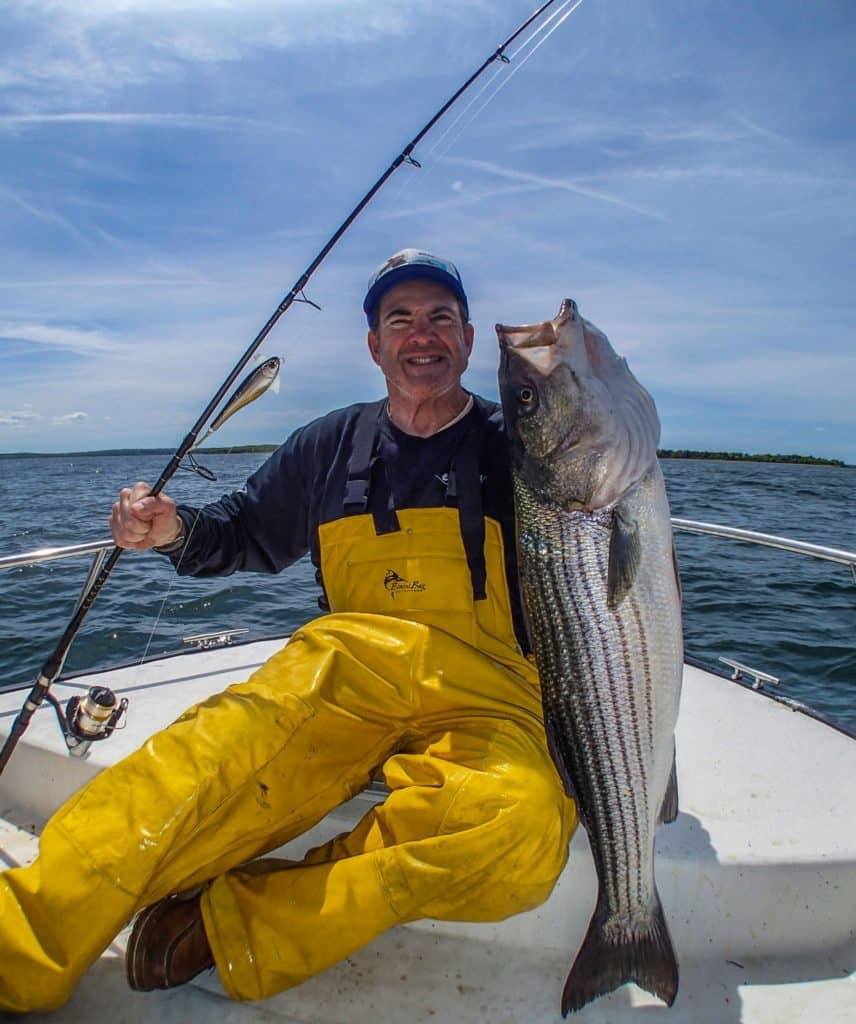 Angler holding a striped bass caught will fishing with a crankbait fishing lure