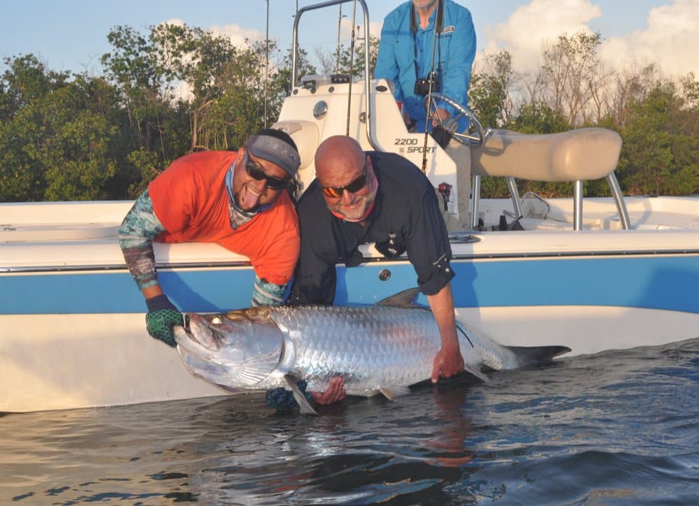 Guide and angler share a moment with 100-pound tarpon before releasing it.