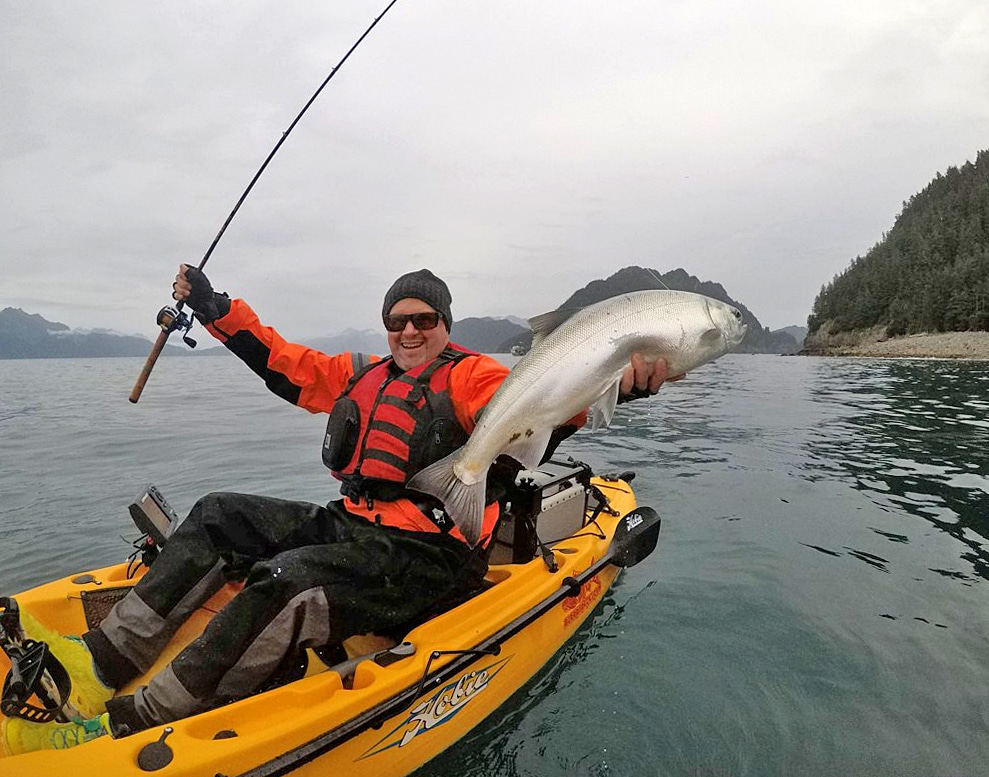 Kayak angler holds an oversized silver salmon