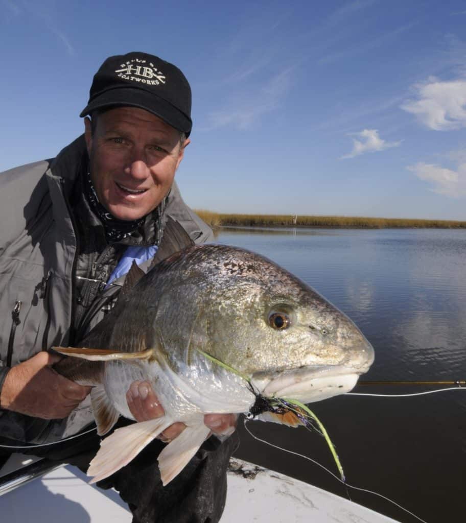 Angler holding a redfish in Louisiana after fly-fishing in a coastal marsh