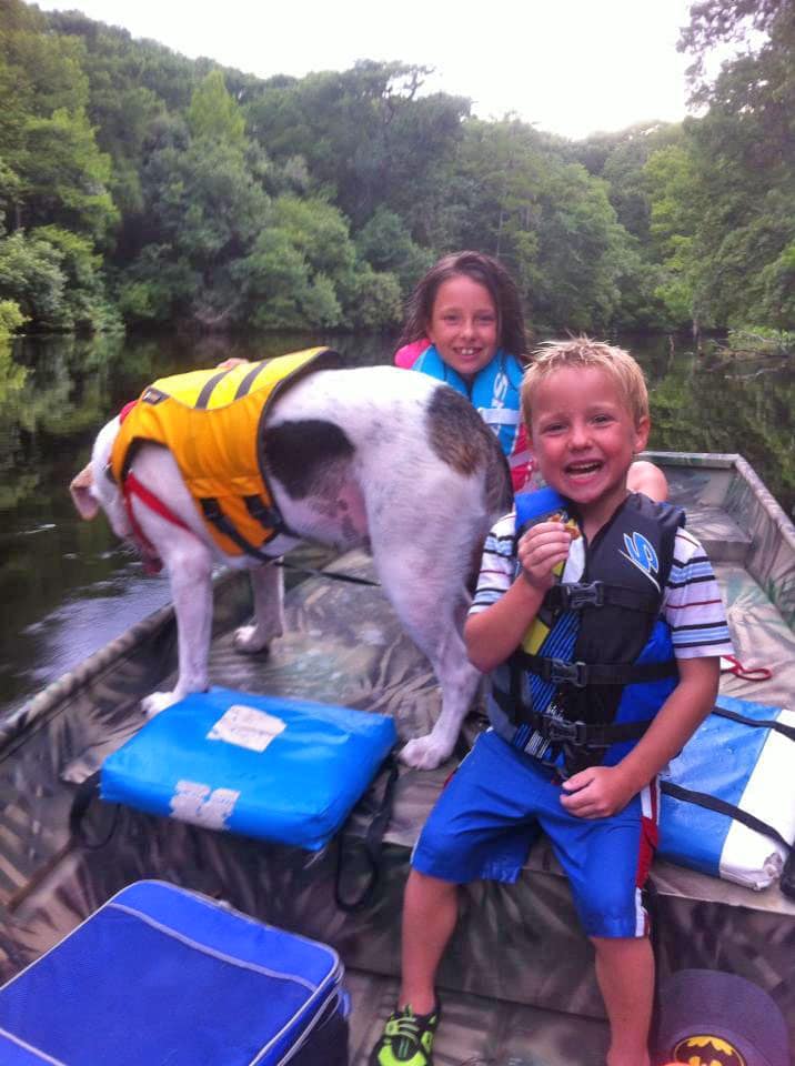 Two kids and a dog wearing life jackets in a boat Withlacoochee River, Florida