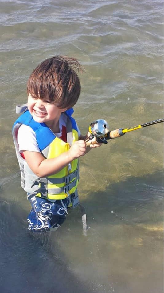 Boy wearing life jacket wade fishing Port Mansfield, Texas