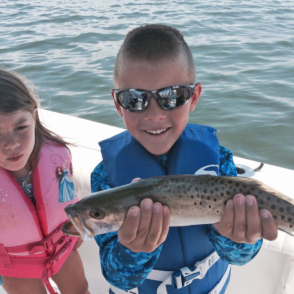 Sister and brother wearing life jackets trout fishing Cedar Key, Florida