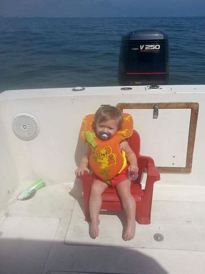 Toddler wearing life jacket on deck of fishing boat Ponce Inlet, Florida