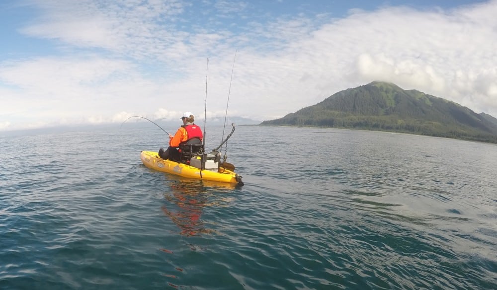 A hooked salmon pulls a kayak along behind it.