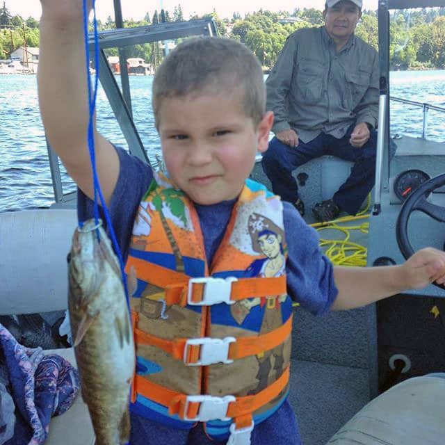 Boy wearing life jacket holding fish