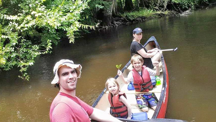 Boys wearing PFDs in canoe with family Hillsborough River, Florida