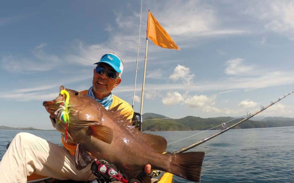 Kayak angler holding grouper caught fishing Panama
