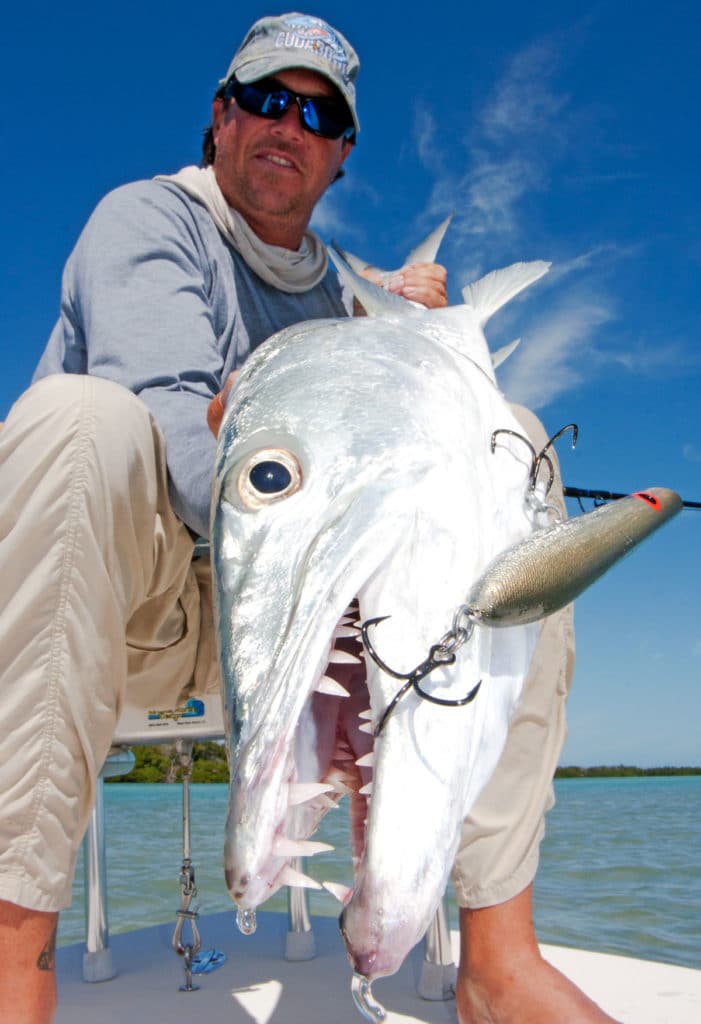 Angler holding barracuda caught fishing Bomber A-Salt Popper
