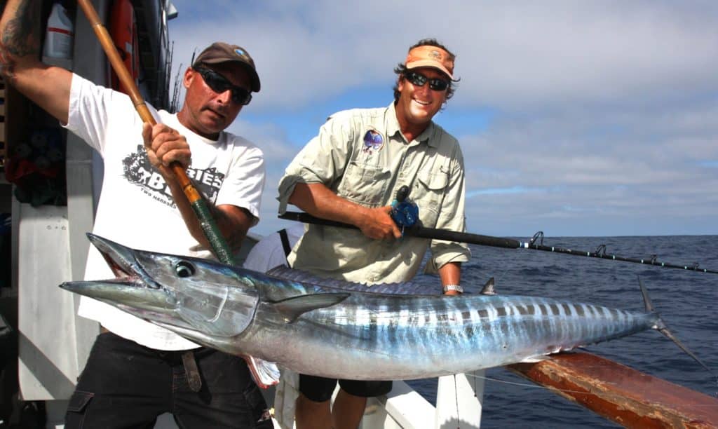 Anglers on a long-range fishing boat holding a wahoo