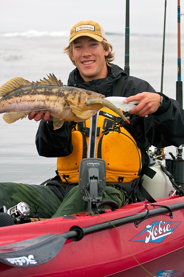 Kayak fisherman holding calico bass caught deep sea fishing swimbait lure