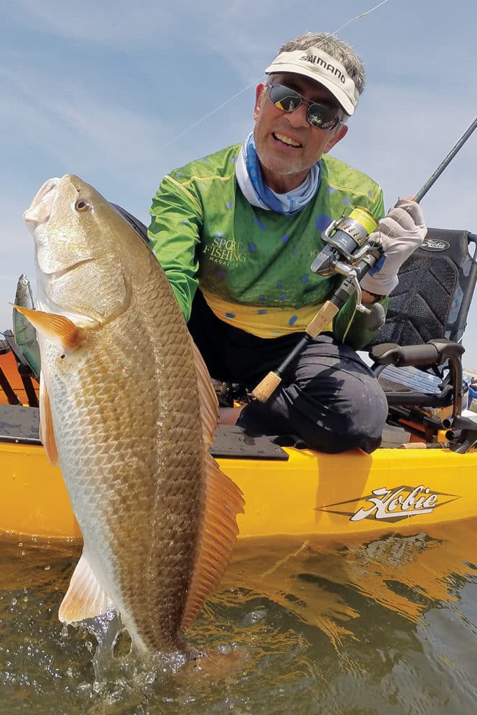 Kayak fisherman holding redfish caught fishing Chandeleurs Islands Louisiana