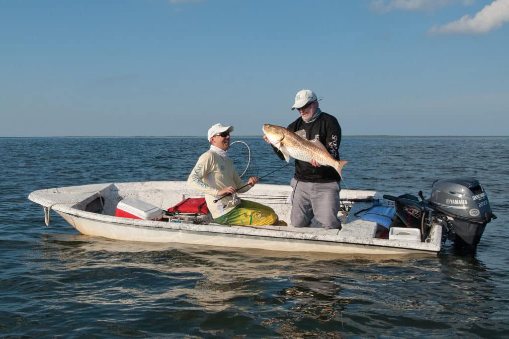 Fishermen holding redfish caught fishing Chandeleur Islands Louisiana