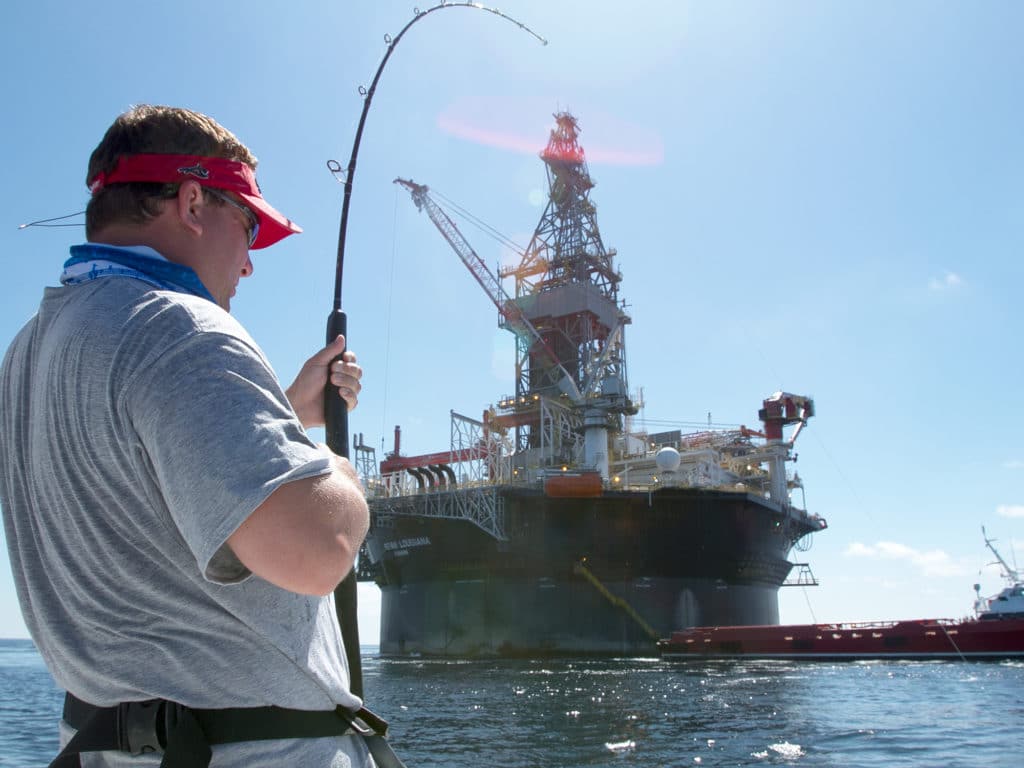 Angler fishing, fighting a fish around an oil rig in the Gulf of Mexico
