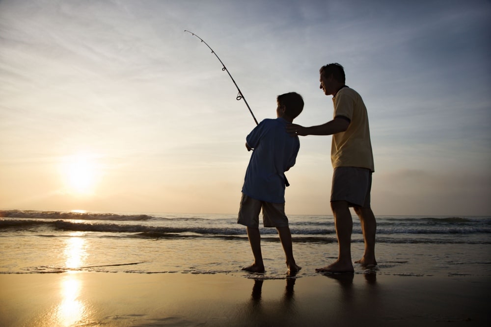 Father and son fish the surf
