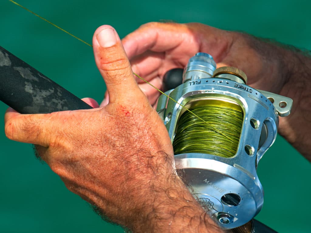 Angler holding a conventional fishing reel filled with braided fishing line