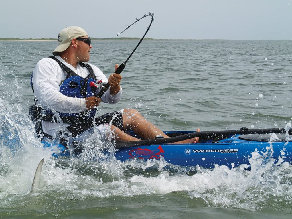 Angler fighting a shark while kayak deep sea fishing