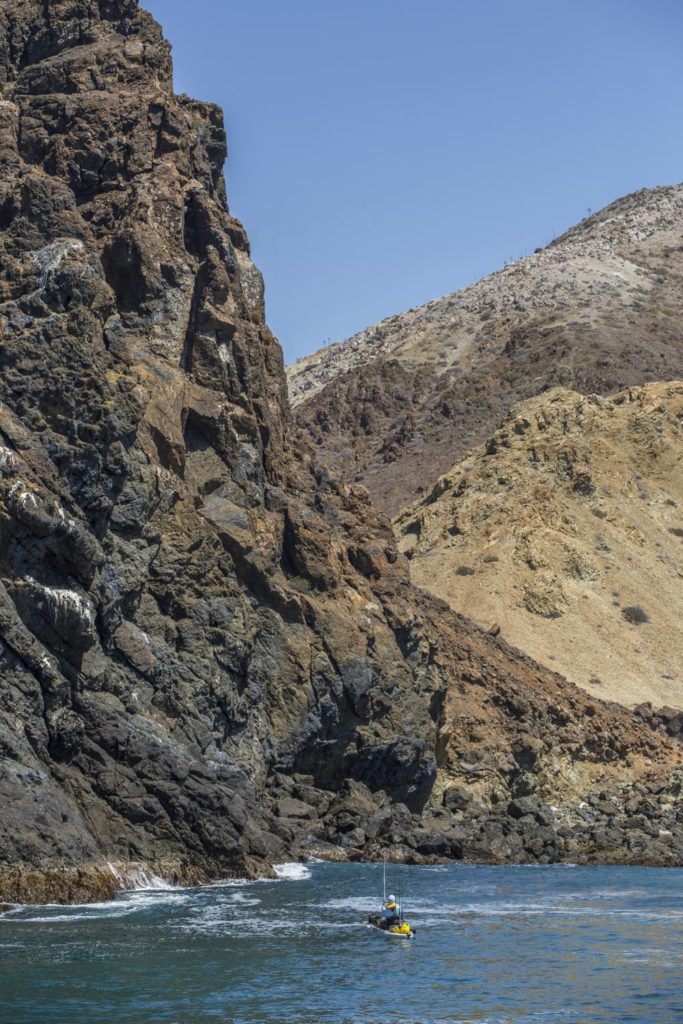 A kayak angler casts beneath towering cliffs on Cedros Island