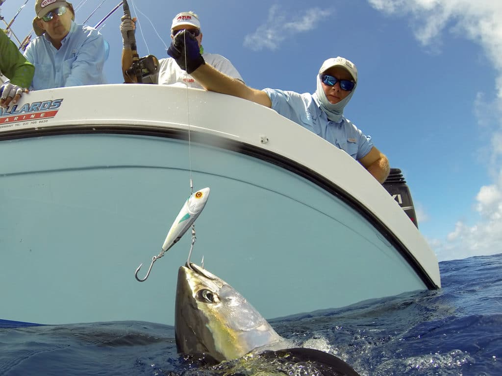Anglers hooked onto a tuna fish while deep-sea fishing