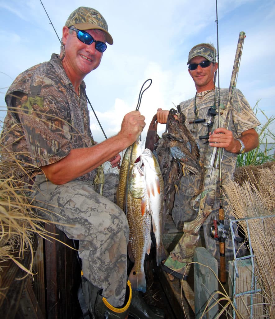 Angler holding redfish, hunter holding ducks