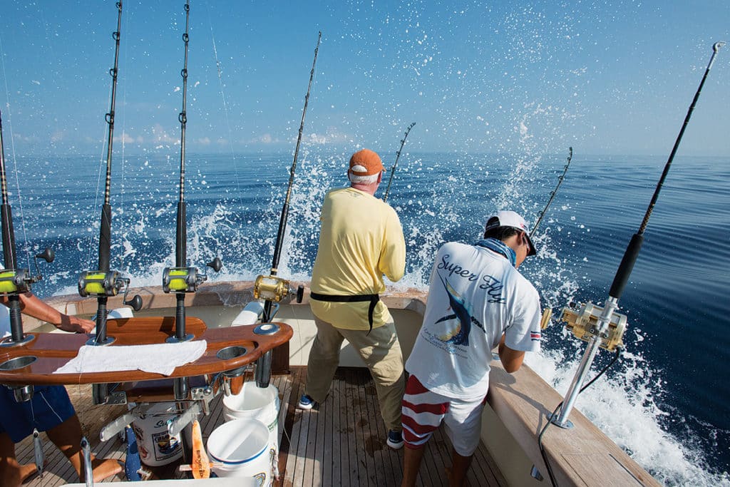 A hooked-up fisherman fighting a fish while the fishing boat backs down on a fish