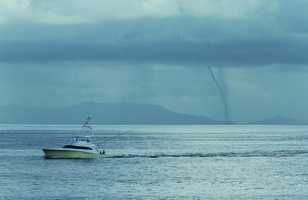 A stormy day on the Pacific as a boat trolls in front of a waterspout