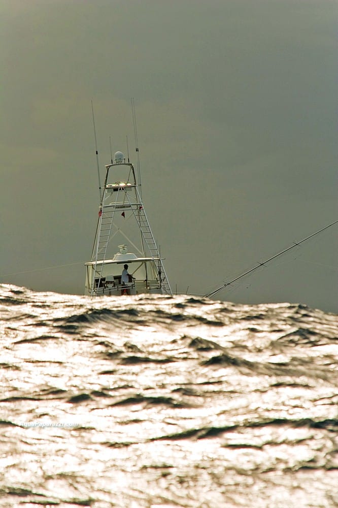 A sport-fishing yacht is hidden behind huge swell