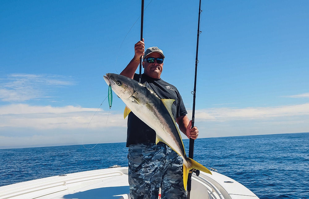 Angler showing gaffed California yellowtail fish