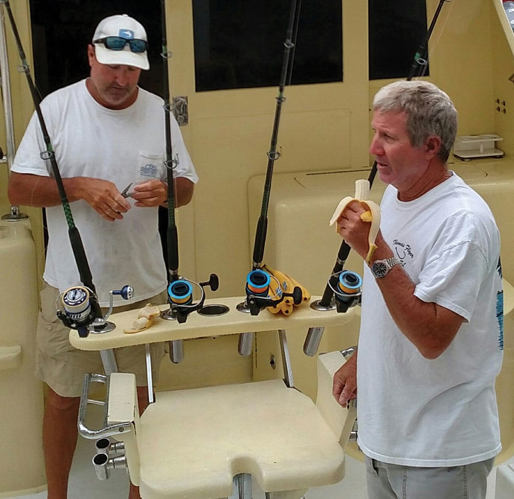 Big-game saltwater fishing captain and mate eating bananas on a boat