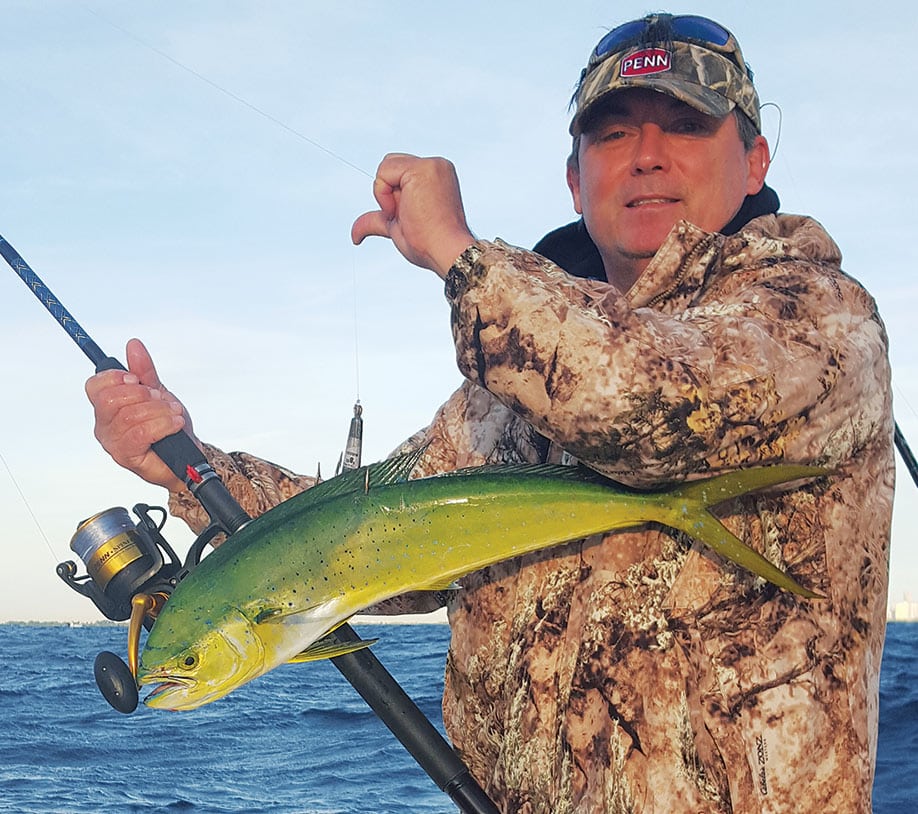 Saltwater angler holding a snagged dolphinfish caught fishing on rod and reel