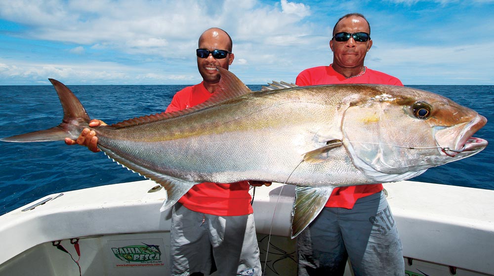 Two anglers holding amberjack caught fishing