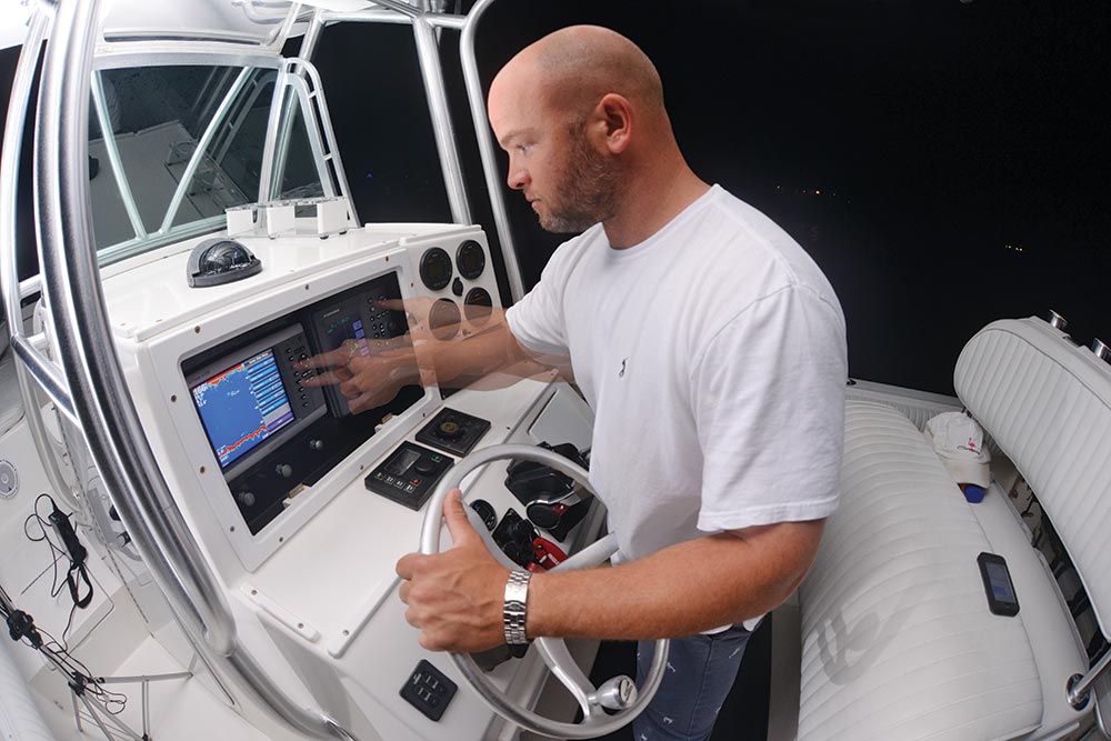 Fisherman adjusting fishing boat fish finder