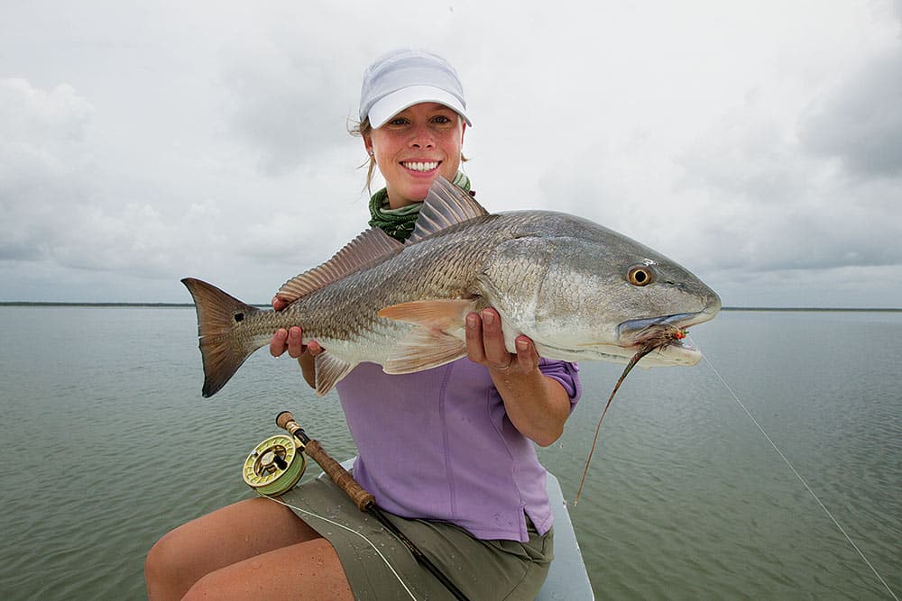 Lady angler holding bull redfish caught fly fishing