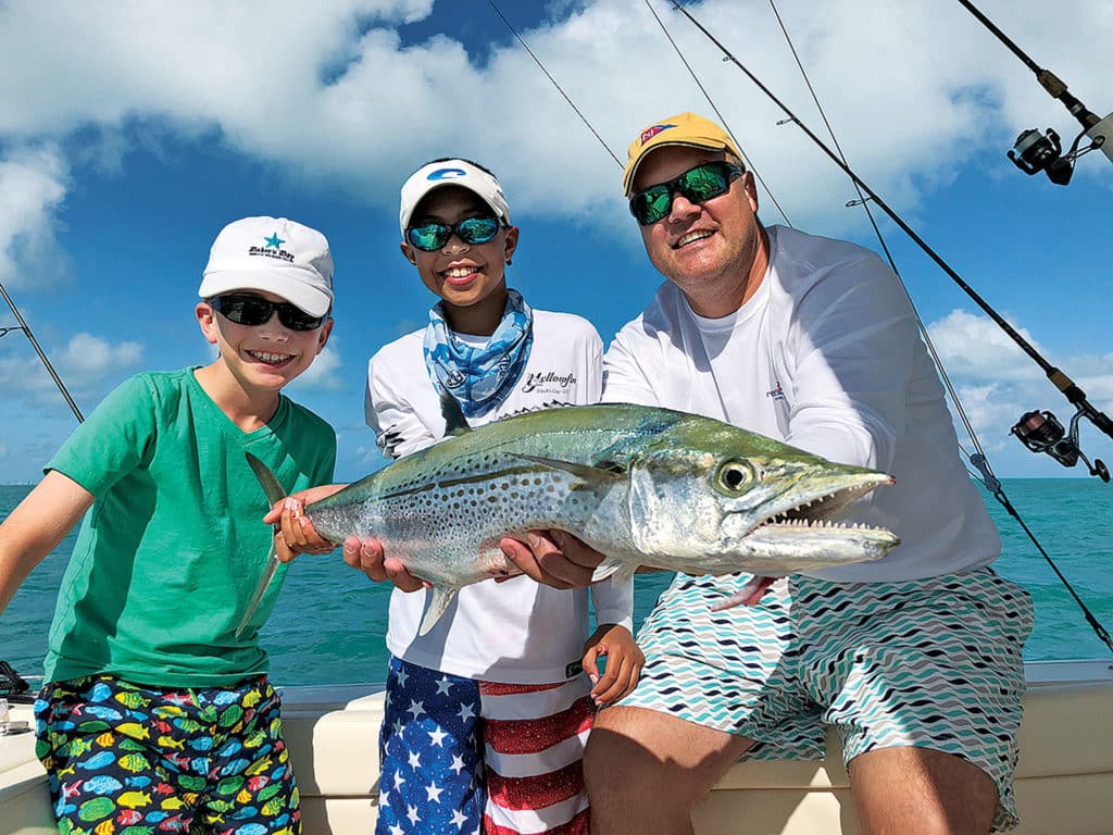 Kids holding a cero mackerel