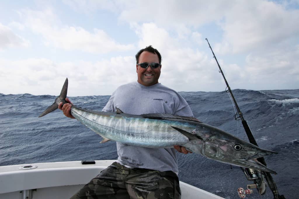 Holding wahoo up on board boat