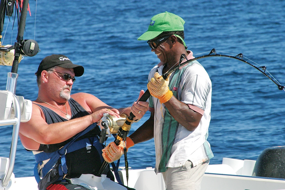 Fishing mate helping angler catch yellowfin tuna fish