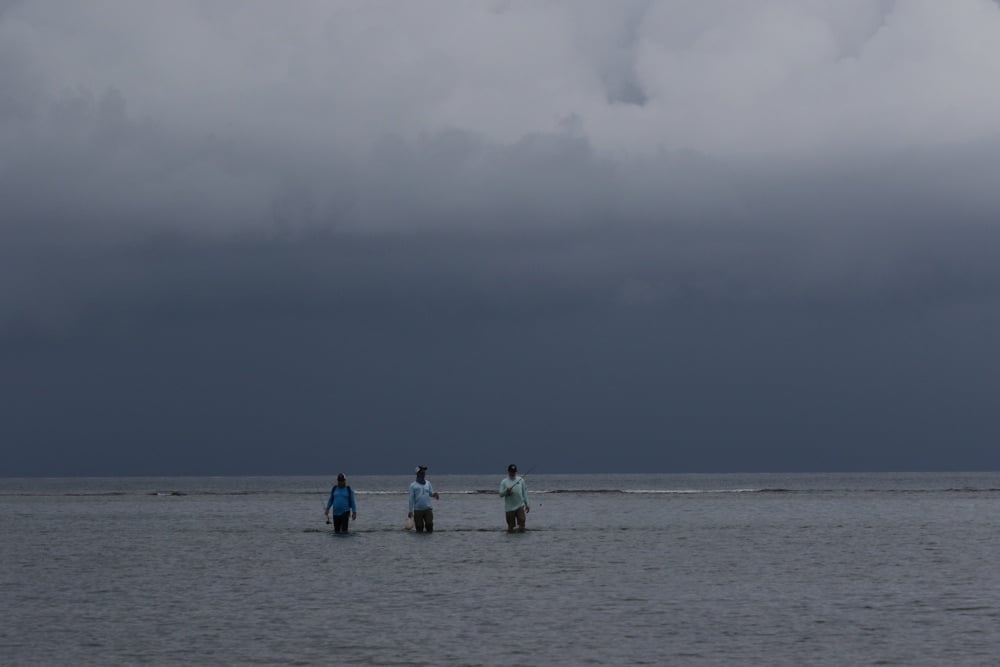 A group of anglers wade Roatan Island flats on a stormy morning.