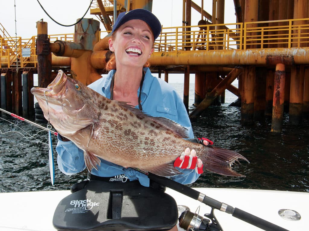 Female angler holding grouper caught fishing bottom structure