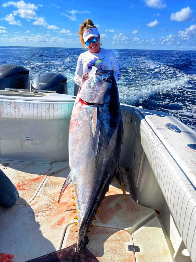 A deckhand holding up a large bigeye tuna.