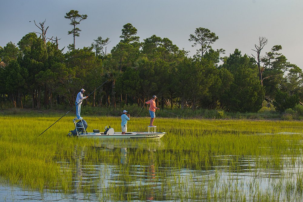 Fly fishing saltwater anglers from flats boat in marsh near Folly Beach, South Carolina