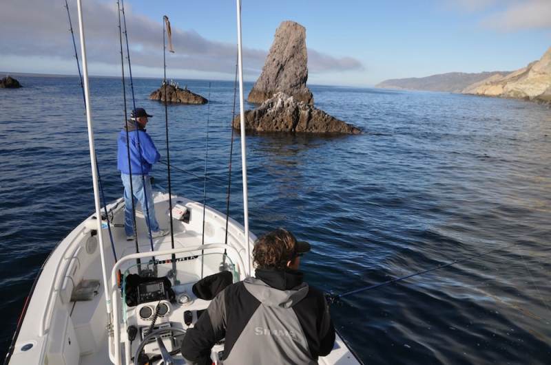 Fishermen fishing rock outcropping deep sea