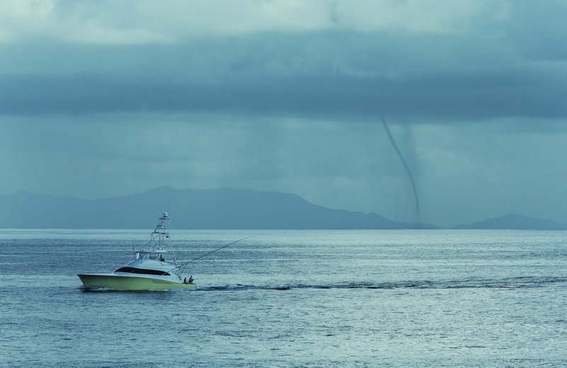 A stormy day on the Pacific as a boat trolls in front of a waterspout